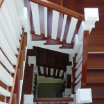 Cherry stairs with a painted wood railing decend form second floor to basement