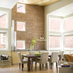 Dining space with high ceilings, a flagstone wall and wood paneling